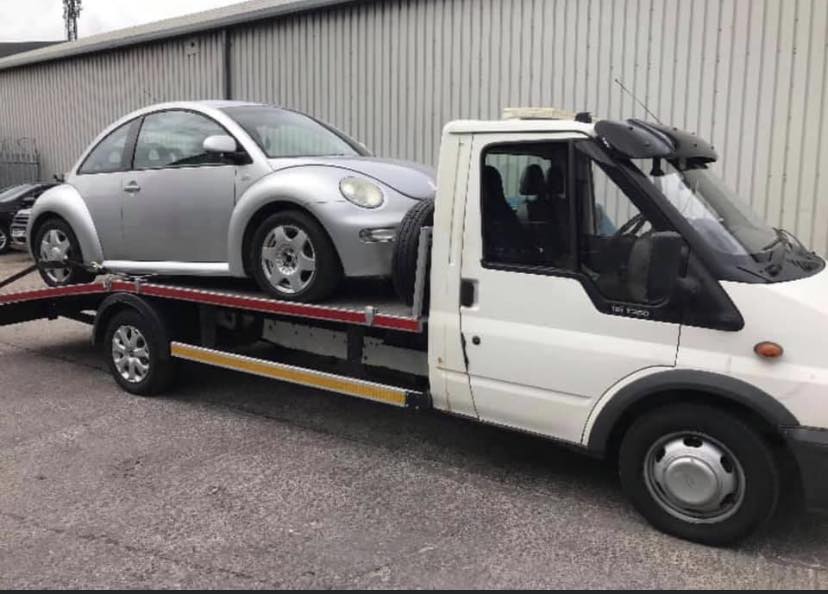 VW Beetle loaded on flatbed truck for scrap
